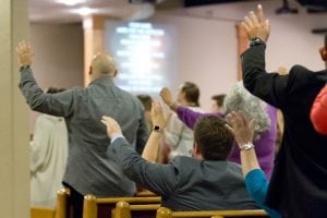 People raising their hands in worship at Christian World Fellowship