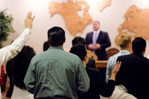 People with their hands raised in worship at Christian World Fellowship